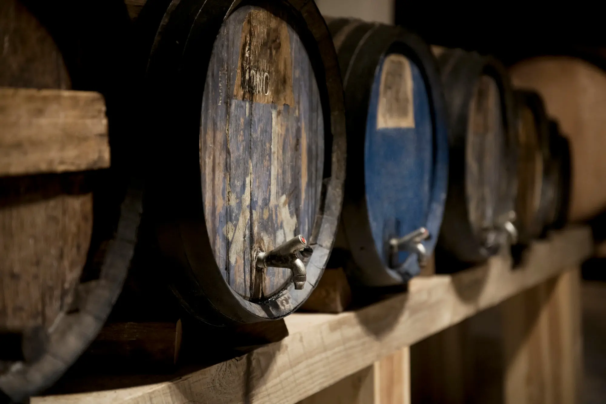 Piccole botti usate con rubinetto, disposte su ripiani in legno
